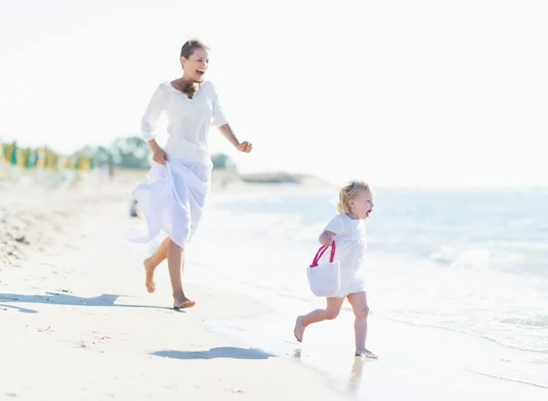 Happy mother and baby playing on sea coast — Stock Photo, Image