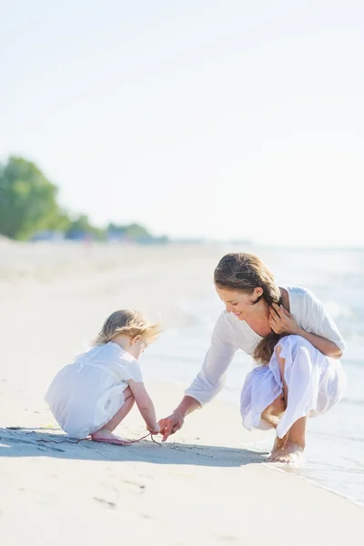 Anne ve bebek kumsalda oynarken — Stok fotoğraf