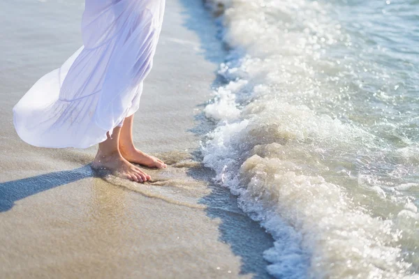 Närbild på ben av ung kvinna som står vid havets strand — Stockfoto