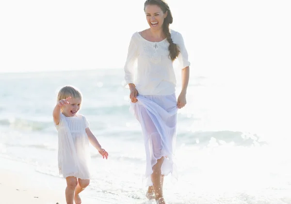 Happy mother and baby walking along sea coast — Stock Photo, Image