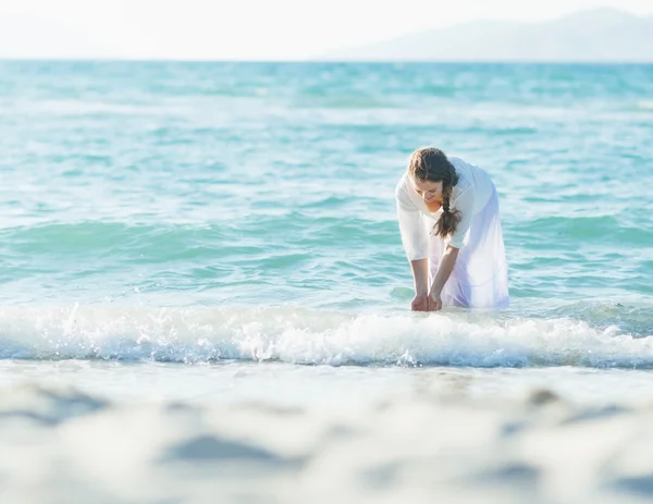 Heureuse jeune femme mouillant les mains en mer — Photo