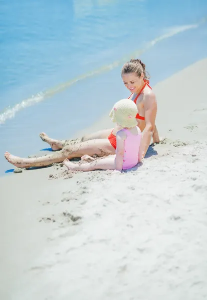 Moeder en baby zittend op strand — Stockfoto