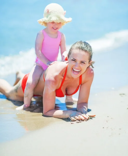 Glad mor og baby leger på stranden - Stock-foto