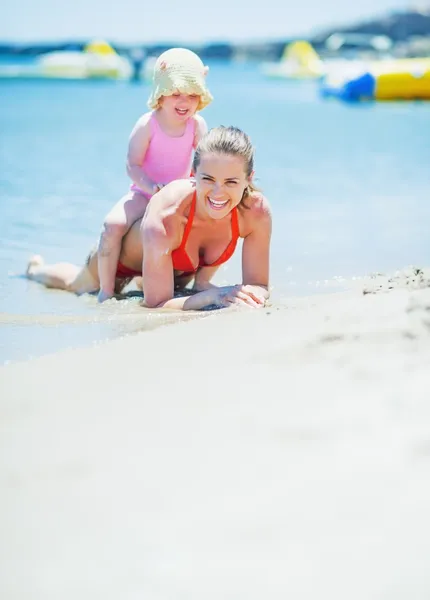 Happy mother and baby playing on sea shore — Stock Photo, Image