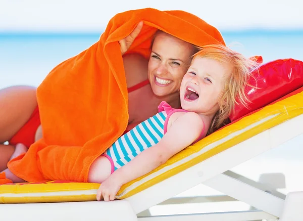 Happy mother and baby laying on chaise-longue and looking on cop — Stock Photo, Image