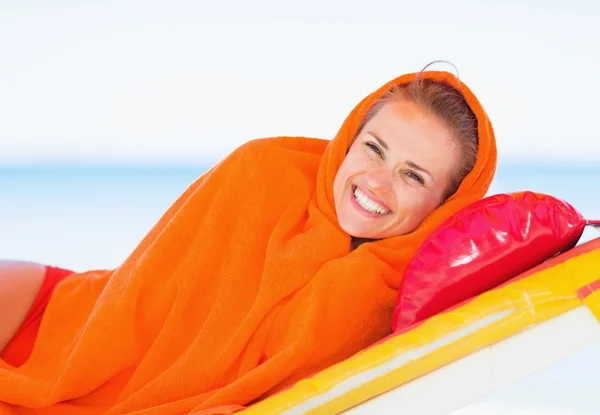 Usměvavá mladá žena zabalená v ručníku na lehátko — Stock fotografie