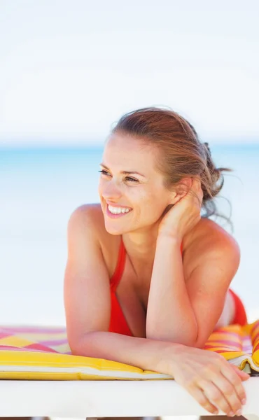 Jonge vrouw op strand op zoek op kopie ruimte glimlachen — Stockfoto