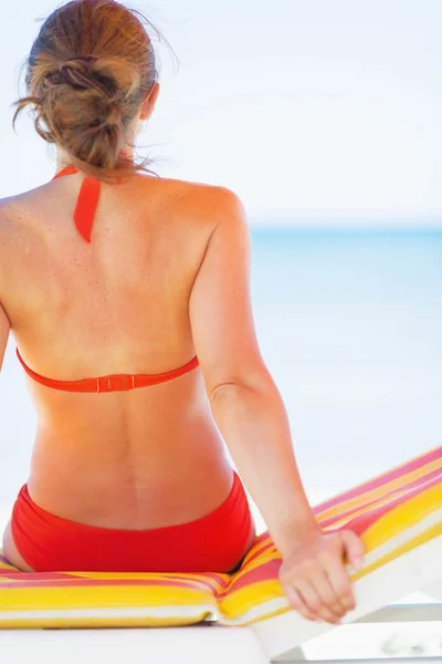 Jonge vrouw zittend op chaise-longue. Achteraanzicht — Stockfoto