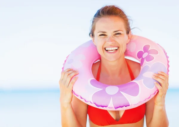 Portret van lachende jonge vrouw op strand met zwemmen ring — Stockfoto