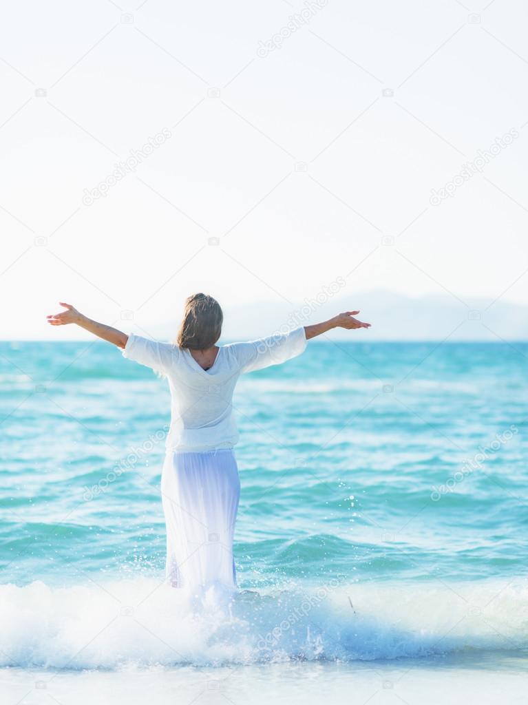 Happy young woman rejoicing on sea shore . rear view