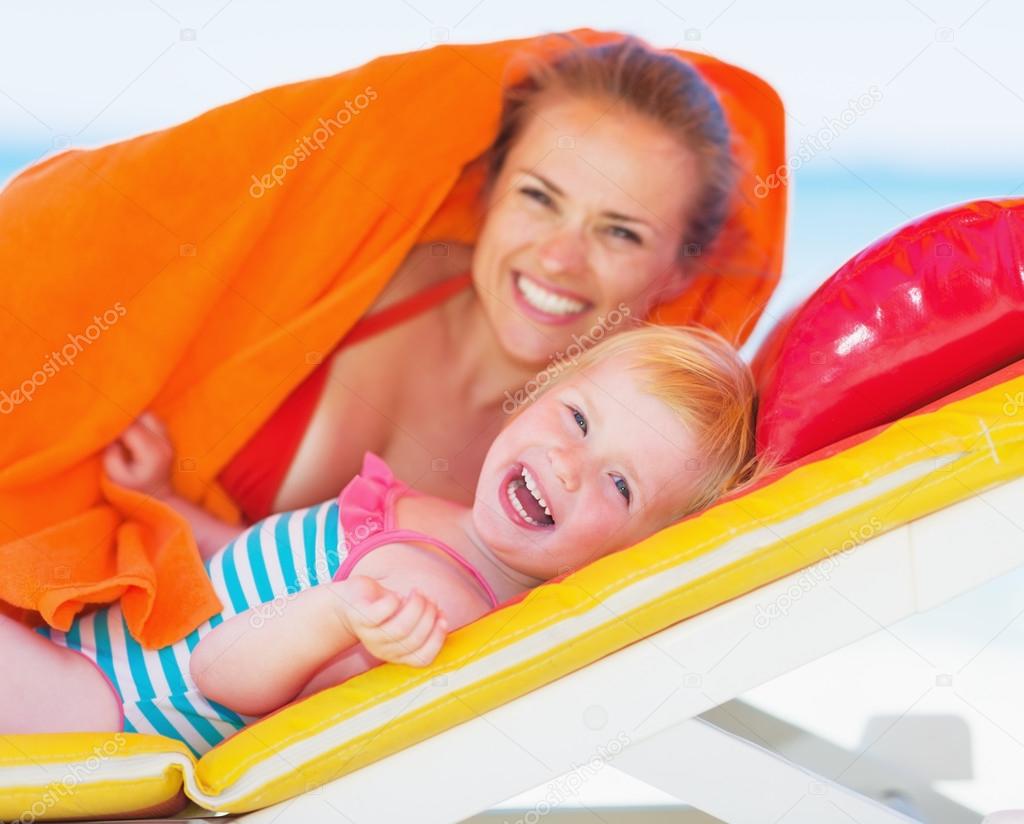 Portrait of happy mother and baby laying on chaise-longue