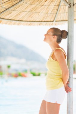 mutlu genç kadın plaj şemsiyesi altında rahatlatıcı