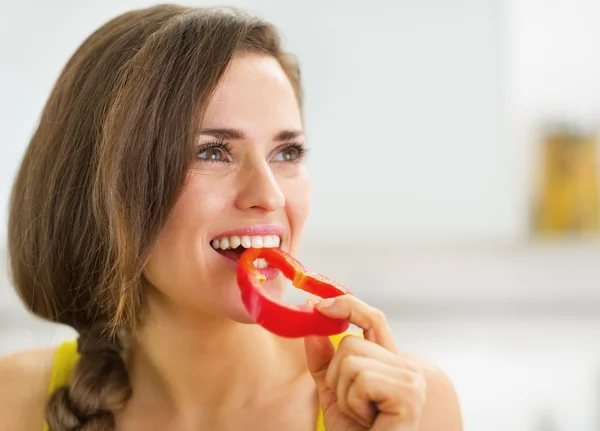 Счастливая молодая женщина, кусающая красный перец — стоковое фото
