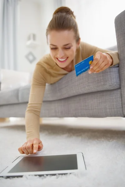 Mujer joven feliz con tarjeta de crédito usando la tableta PC mientras que pone — Foto de Stock