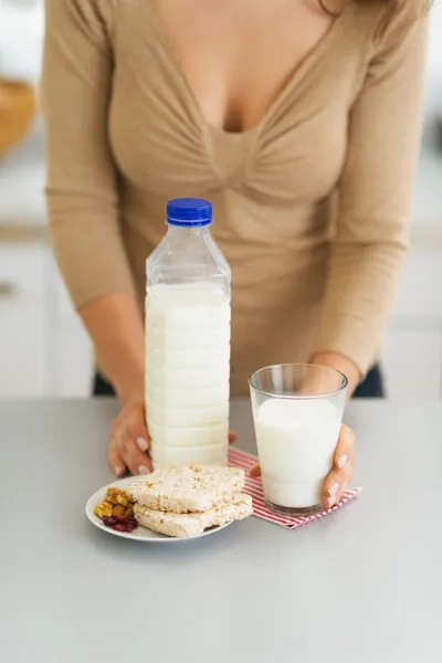 Κινηματογράφηση σε πρώτο πλάνο στο ποτήρι γάλα και ξεροψημένο ψωμί και γυναίκα στο παρασκήνιο — Φωτογραφία Αρχείου