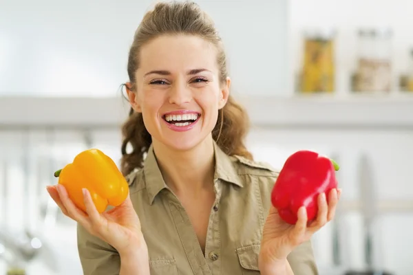 Gelukkig jonge huisvrouw houden van rode en gele paprika — Stockfoto