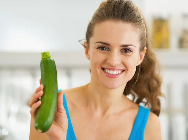 Souriant jeune femme montrant courgettes fraîches — Photo