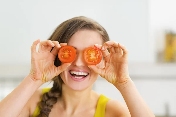 Gelukkig jonge vrouw met twee segmenten van tomaat in front of eyes — Stockfoto