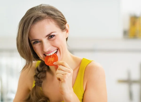 Felice giovane donna avendo un morso di pomodoro rosso — Foto Stock