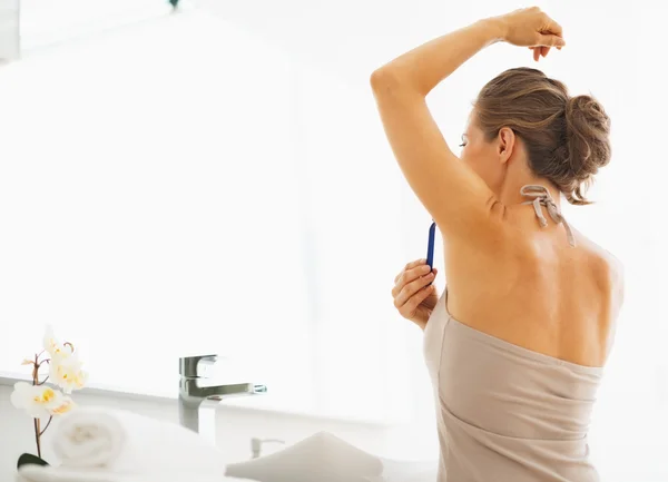 Woman shaving armpit in bathroom — Stock Photo, Image