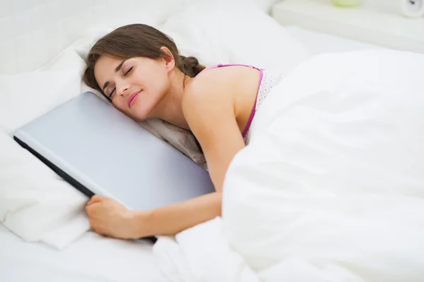 Jovem mulher abraçando laptop enquanto dorme — Fotografia de Stock