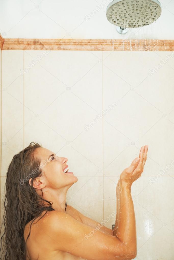 Happy young woman catching water drops in shower