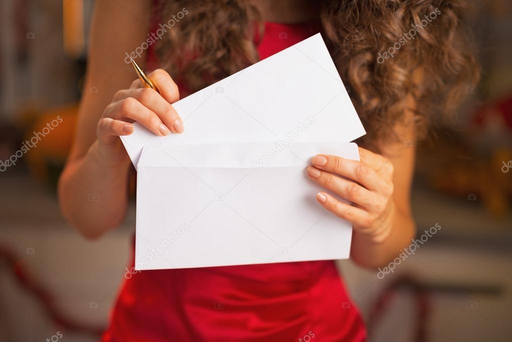 Closeup on woman in red dress putting christmas letter