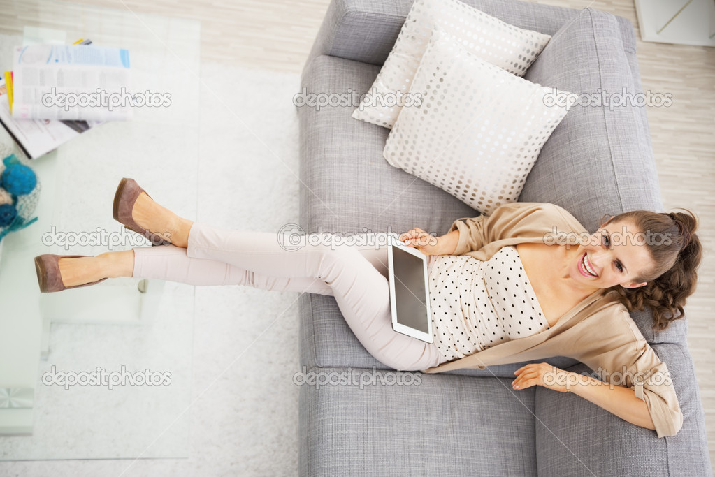 Smiling young woman sitting on sofa with tablet pc