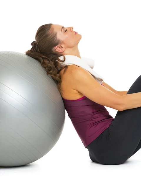 Mujer joven y cansada sentada cerca de la pelota fitness —  Fotos de Stock