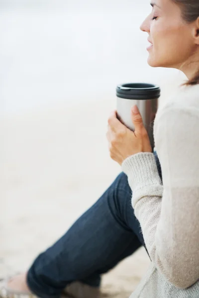 Frau im Pullover am Strand mit Tasse — Stockfoto