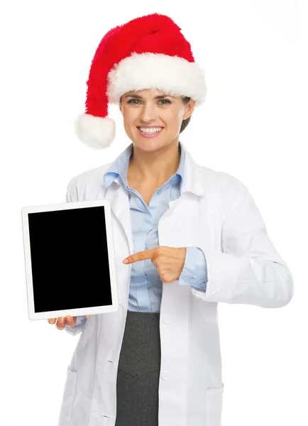 タブレット pc で指しているサンタ帽子の女性を幸せな医者 — ストック写真