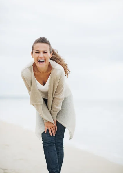 Sonriente mujer joven en suéter divertirse en la playa solitaria — Foto de Stock