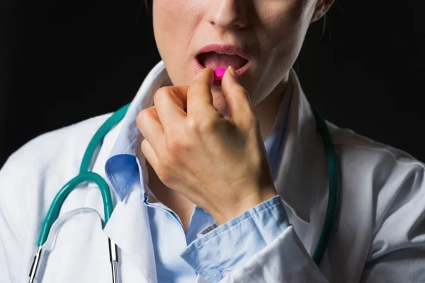 Close-up em médico mulher comer pílula isolada em preto — Fotografia de Stock