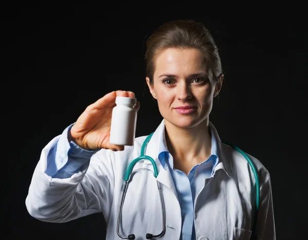 Médico mulher mostrando frasco de remédio no fundo preto — Fotografia de Stock