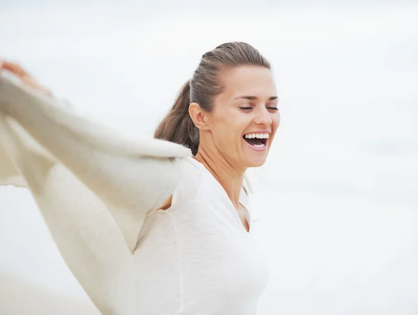 Счастливая молодая женщина в свитере веселится на одиноком пляже — стоковое фото