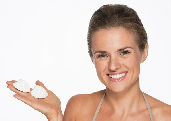 Mujer joven sonriente mostrando conchas marinas — Foto de Stock