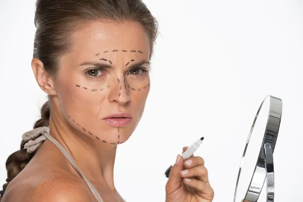 Woman with plastic surgery marks on face holding mirror and mark — Stock Photo, Image