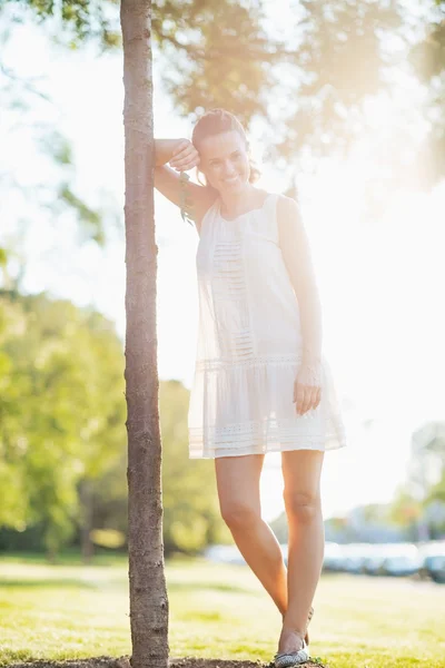 Porträt einer lächelnden jungen Frau, die neben einem Baum steht — Stockfoto