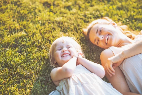 Sonriente madre y bebé tendidos en el prado — Foto de Stock