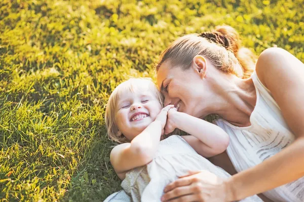 Mãe feliz e bebê deitado no prado — Fotografia de Stock