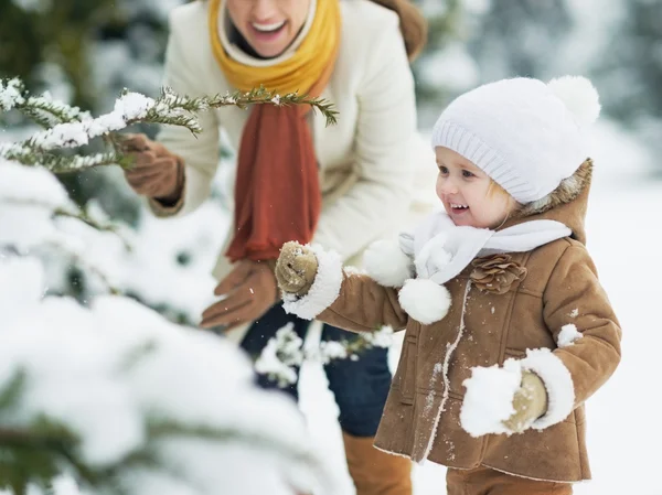 Lycklig mor och barn leker med snö på gren — Stockfoto