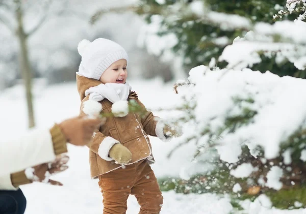 Happy mother and baby playing with snow on branch — Stock Photo, Image