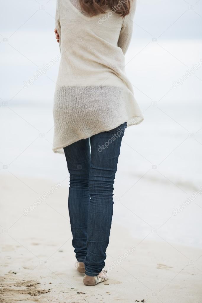 Young woman in sweater walking on lonely beach