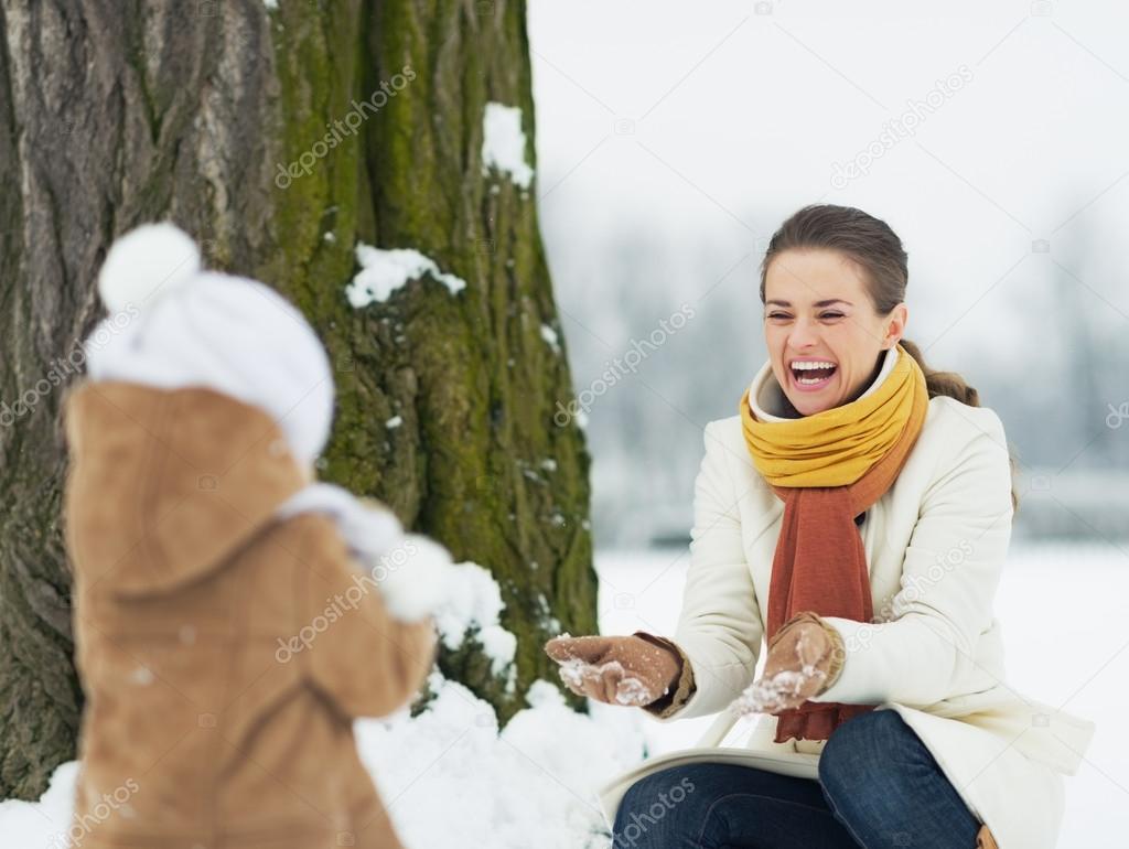 Happy mother and baby playing outdoors in winter