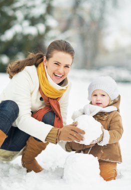 mutlu anne ve bebek kış Park'ta kardan adam yapma