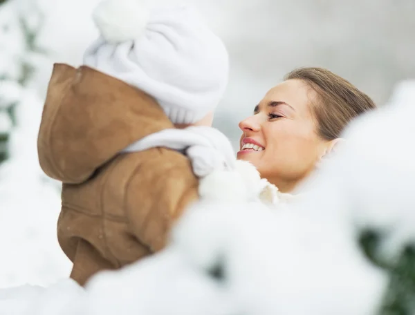 Mother and baby in winter park behind snowy branches — Stock Photo, Image