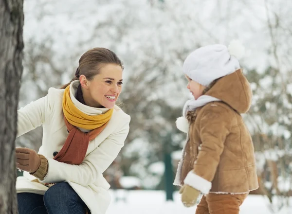 Glückliche Mutter spielt mit Baby im Winterpark — Stockfoto