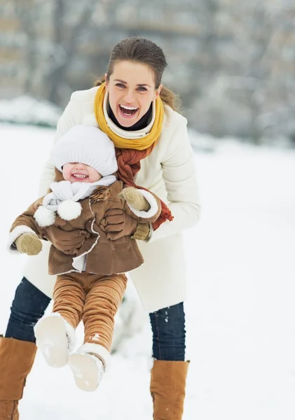 Feliz madre jugando con el bebé en el parque de invierno — Foto de Stock