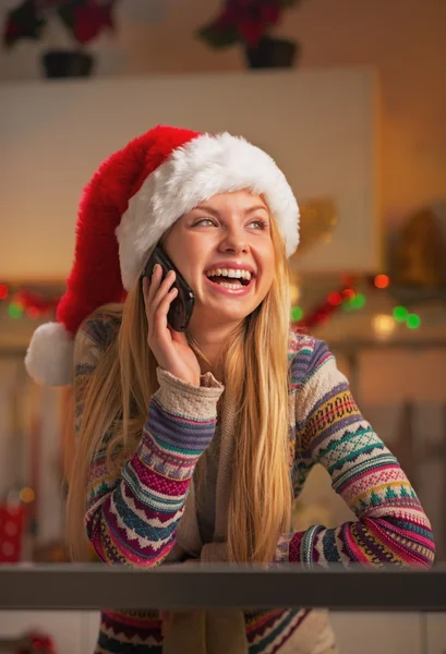 Souriant adolescent fille en santa chapeau parler téléphone mobile dans la cuisine décorée de Noël — Photo