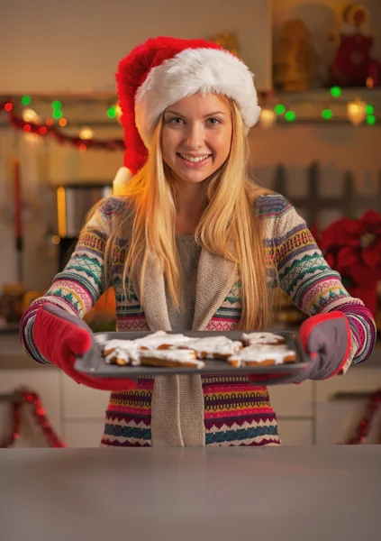 Smiling teenage girl in santa hat showing pan of fresh cookies — Stock Photo, Image